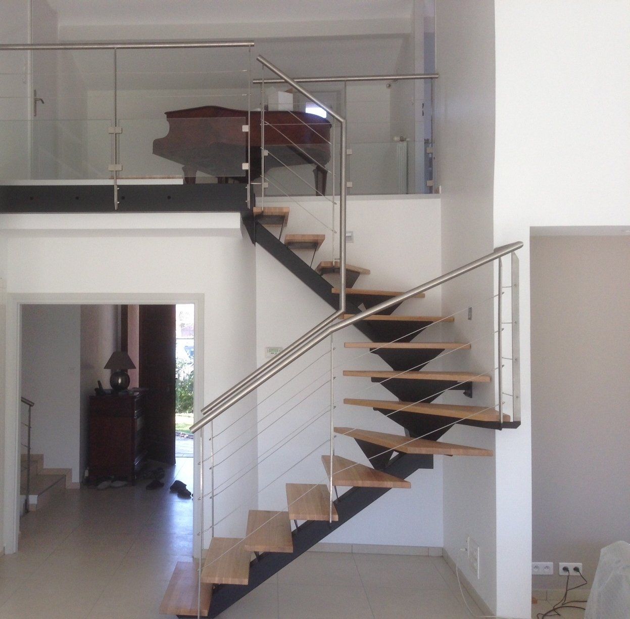 Escalier 2/4 tournant, limon central avec marches bois Garde-corps escalier en inox avec câbles Garde-corps étage en inox avec câbles en partie haute et verre en partie basse.