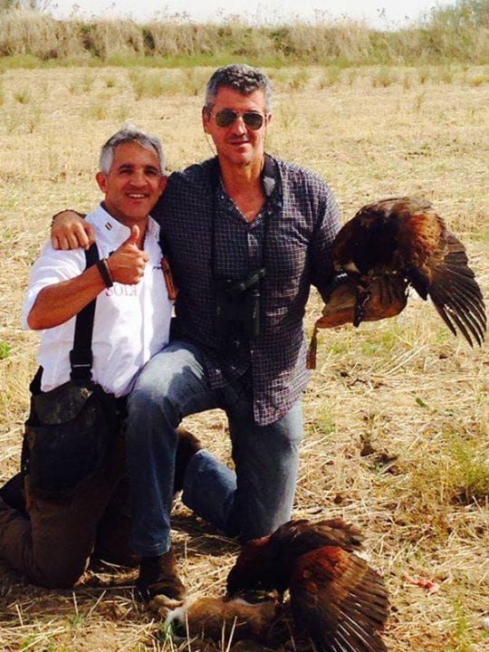 Dos hombres posan para una foto con dos pájaros.