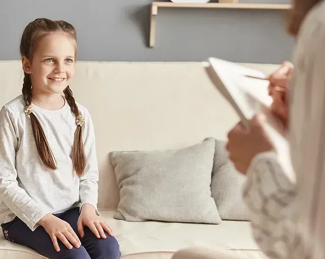 Una niña está sentada en un sofá hablando con un médico.