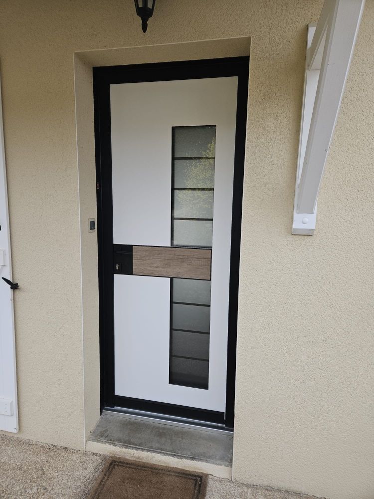 Porte d'entrée avec encadrement noir, panneau en verre dépoli et mur extérieur beige.