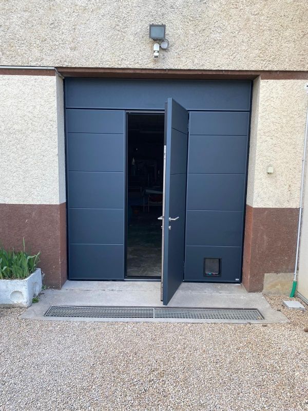 L'entrée d'un bâtiment bleu foncé est ouverte, une porte est entrouverte, encadrée par des murs beiges et une petite lumière est éclairée au-dessus.
