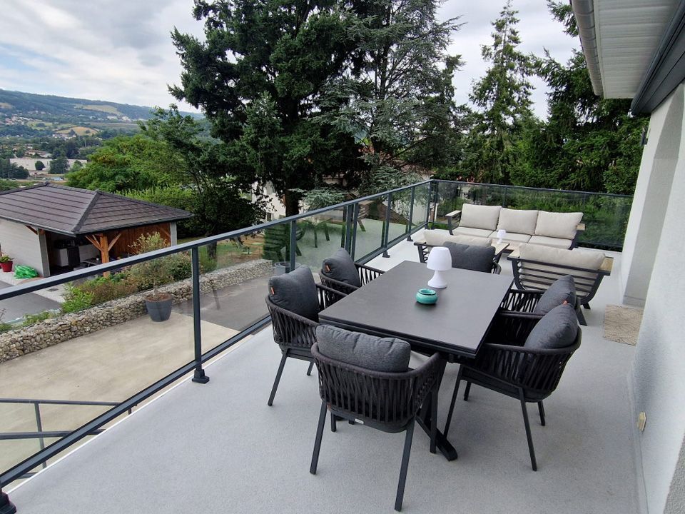 Salon de jardin sur une terrasse munie d'un garde corps en verre