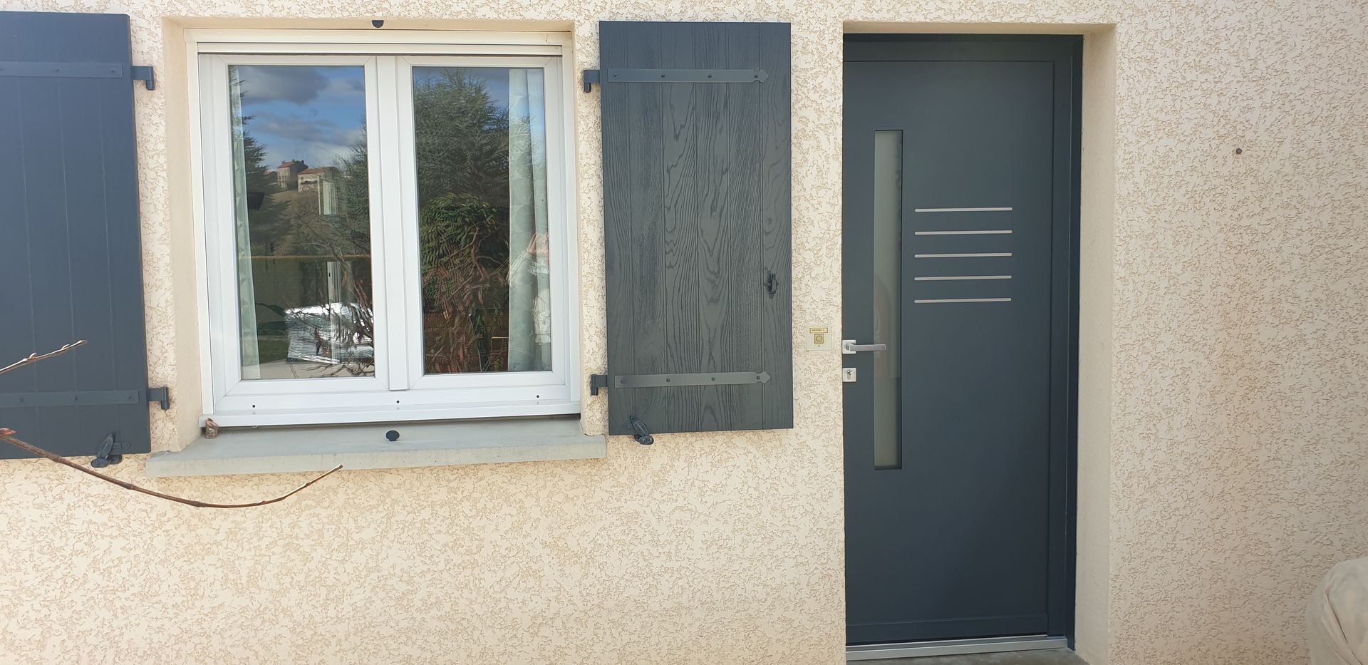 Une fenêtre avec des volets gris et une porte grise