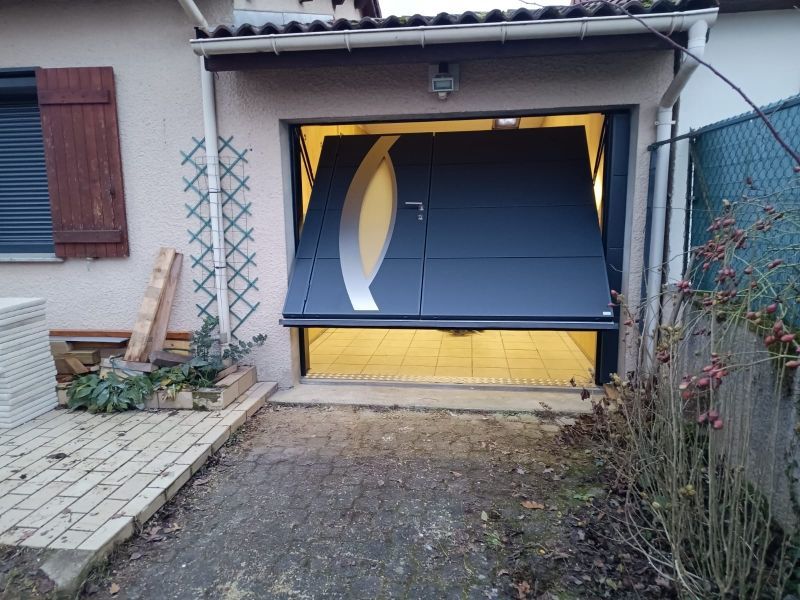 Porte de garage bleue entrouverte, située à l'avant d'une maison, vue depuis l'allée.
