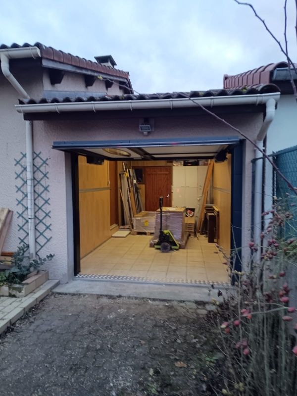 Garage ouvert avec outils et matériaux de construction à l'intérieur d'une entrée de maison