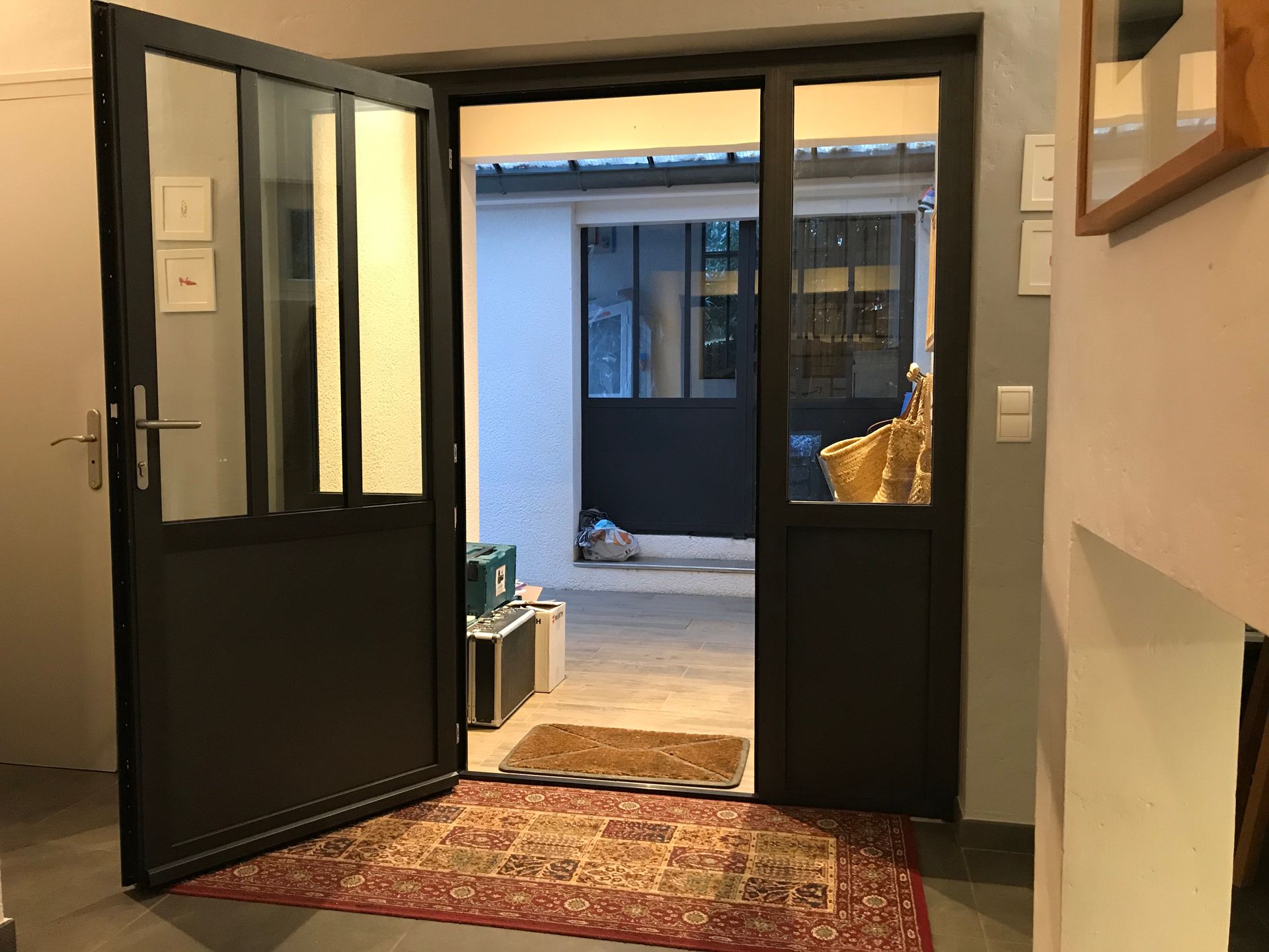 Porte d'entrée ouverte avec un grand carreau vitré 