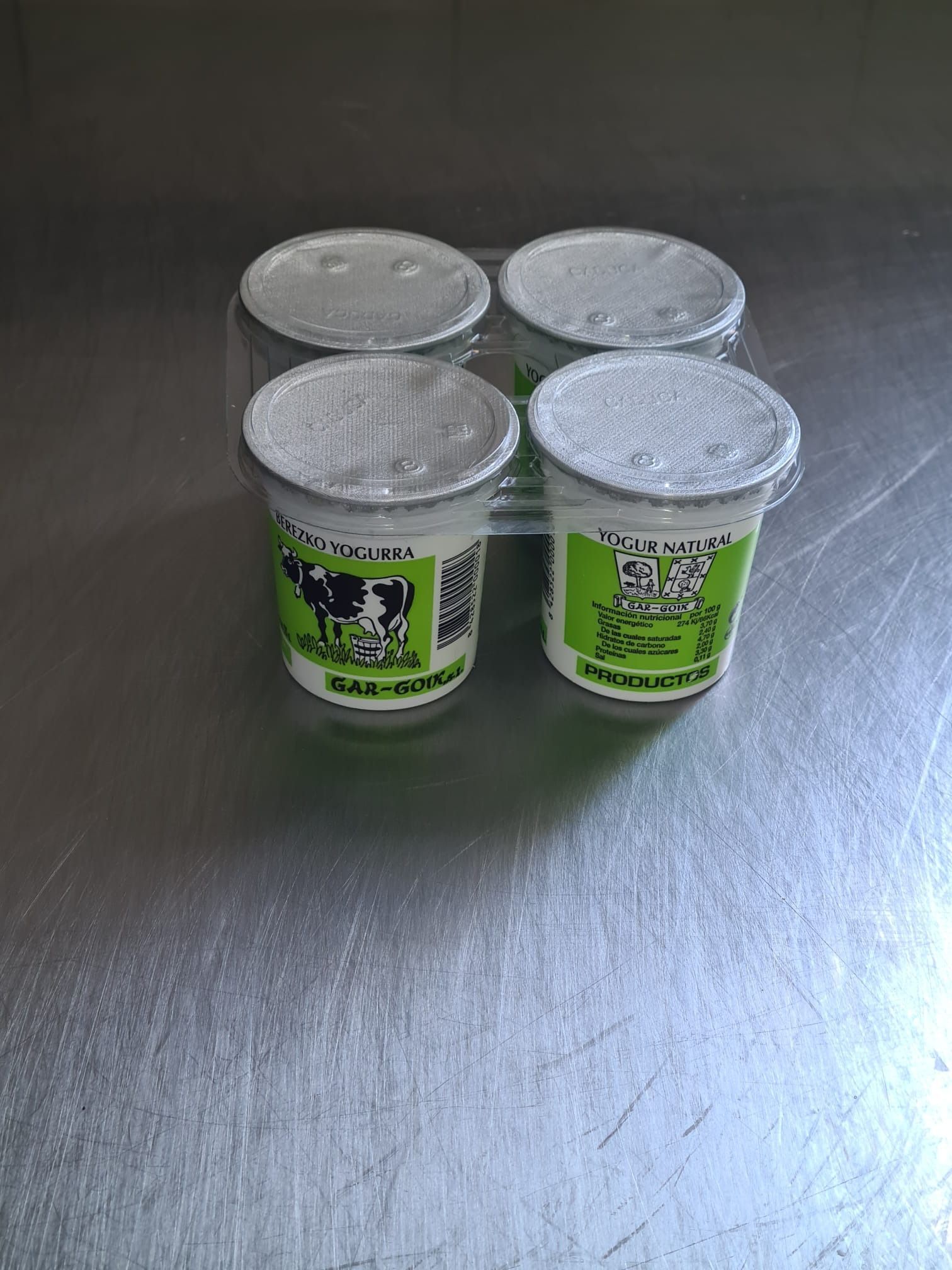 Cuatro tazas de yogur están sobre una mesa de metal.