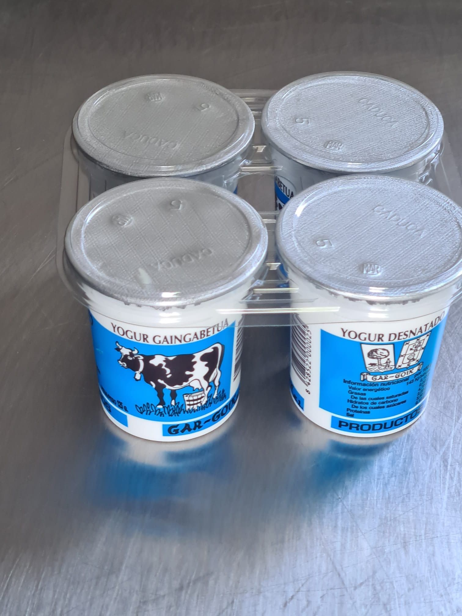Cuatro envases de yogur con una vaca en la etiqueta.