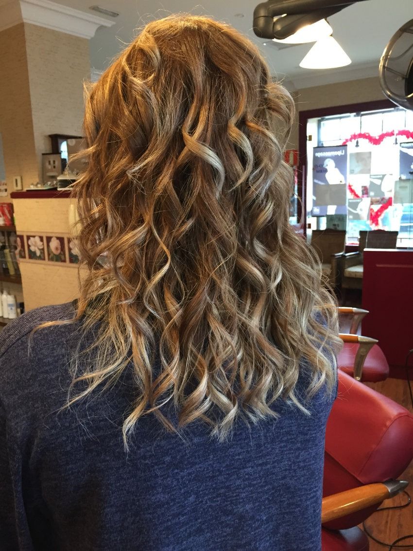 Una mujer con cabello largo y rizado está sentada en una silla en un salón.
