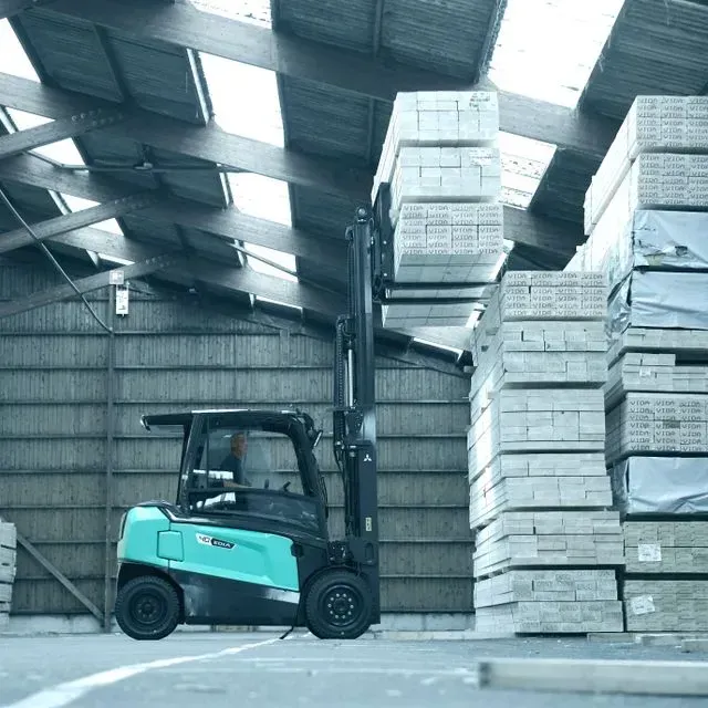 Una carretilla elevadora está estacionada frente a una gran pila de ladrillos.