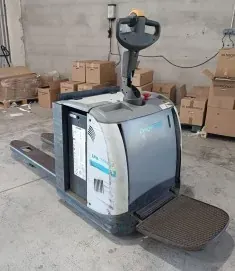 Una transpaleta se encuentra en un almacén al lado de cajas.