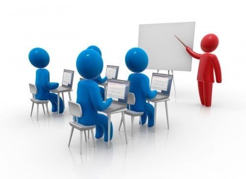 Un hombre está dando una presentación a un grupo de personas sentadas en escritorios con computadoras portátiles.
