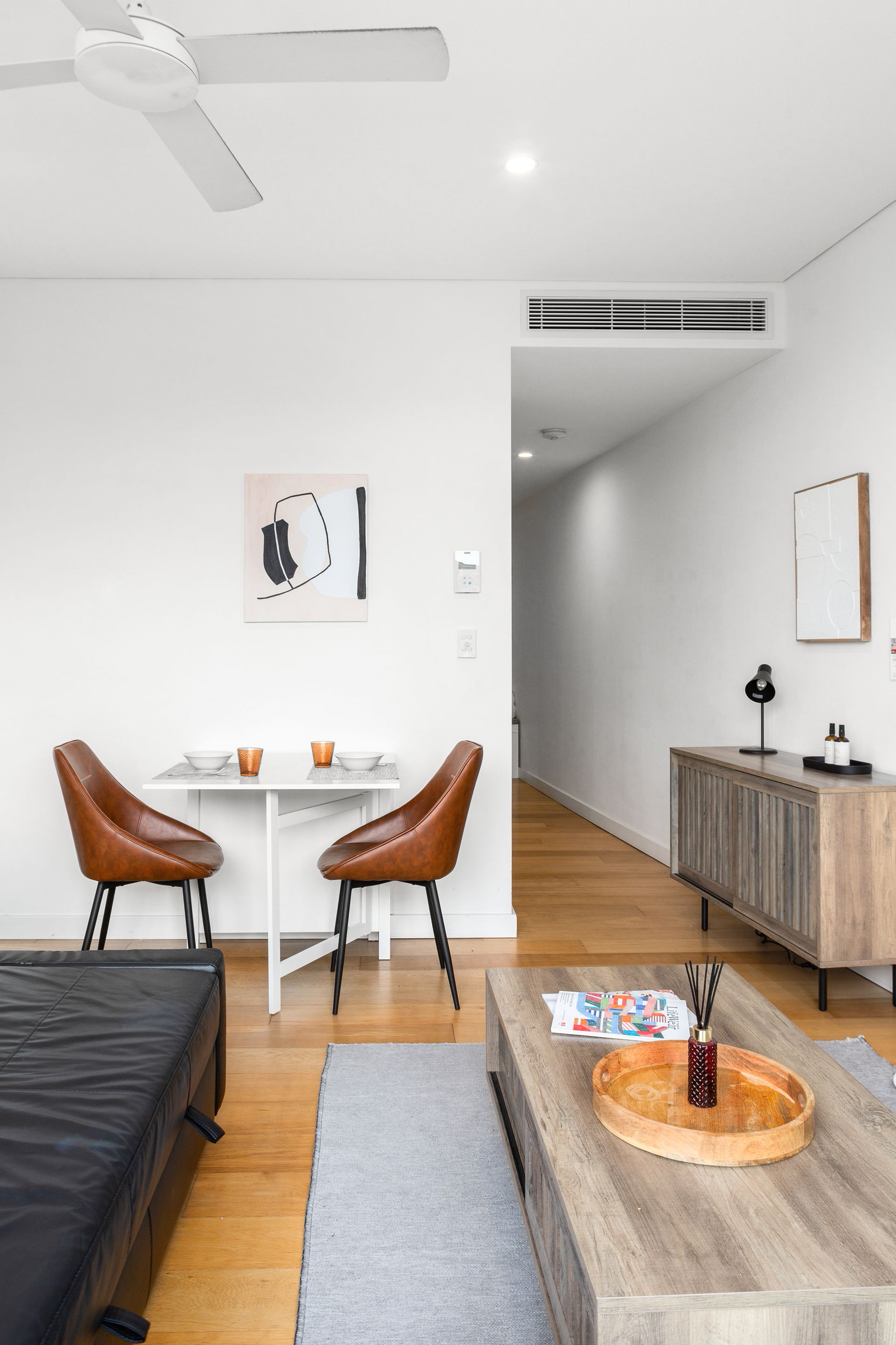 Modern living-dining area with white walls, wood floors, brown chairs, and a gray sofa corner