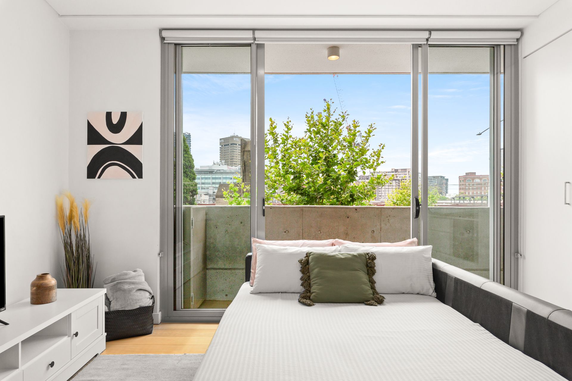 Modern bedroom with a bed, sliding glass doors, and a bright balcony view
