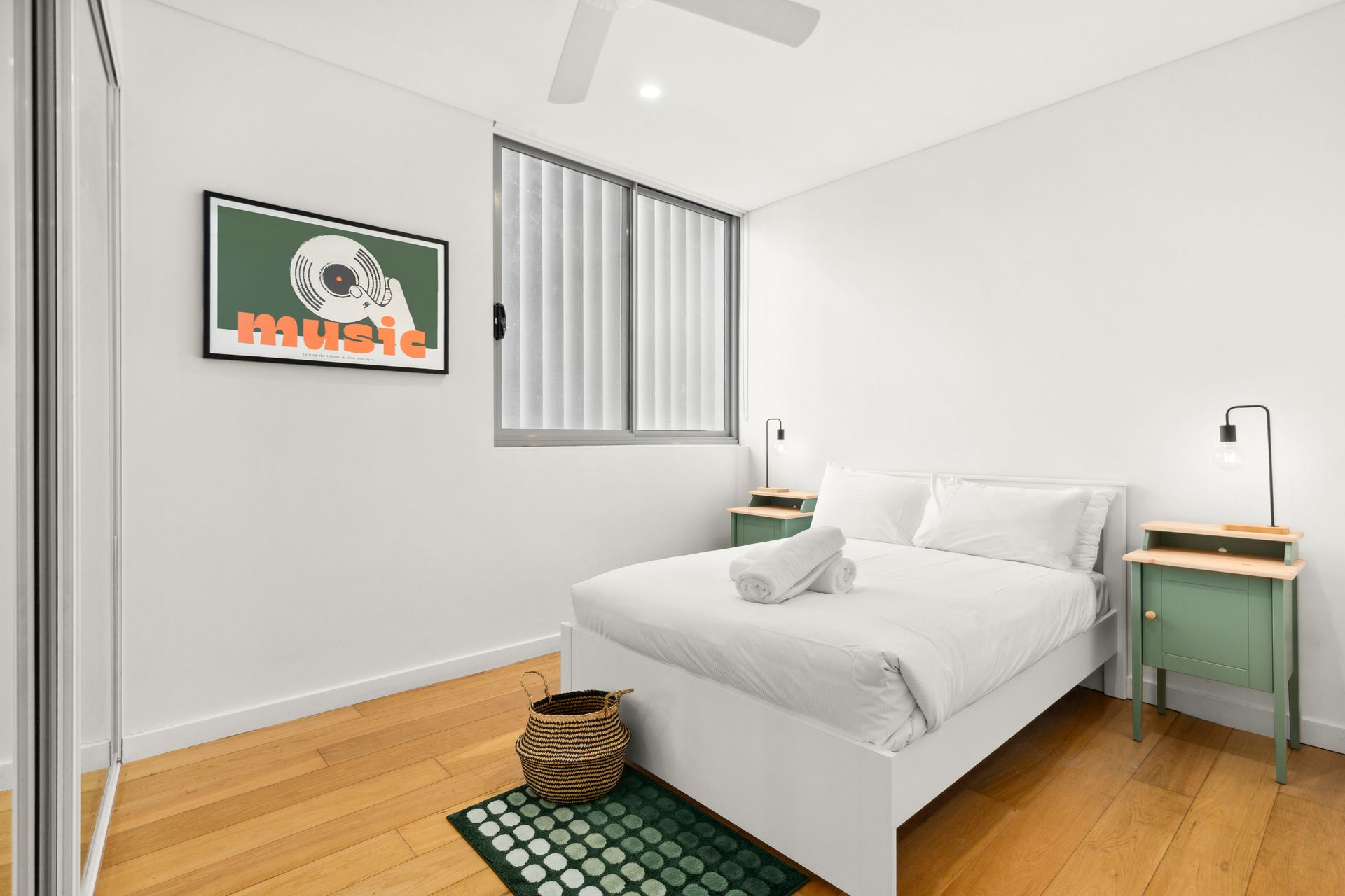 Minimal white bedroom with a bed, bedside tables, window, and wooden floor