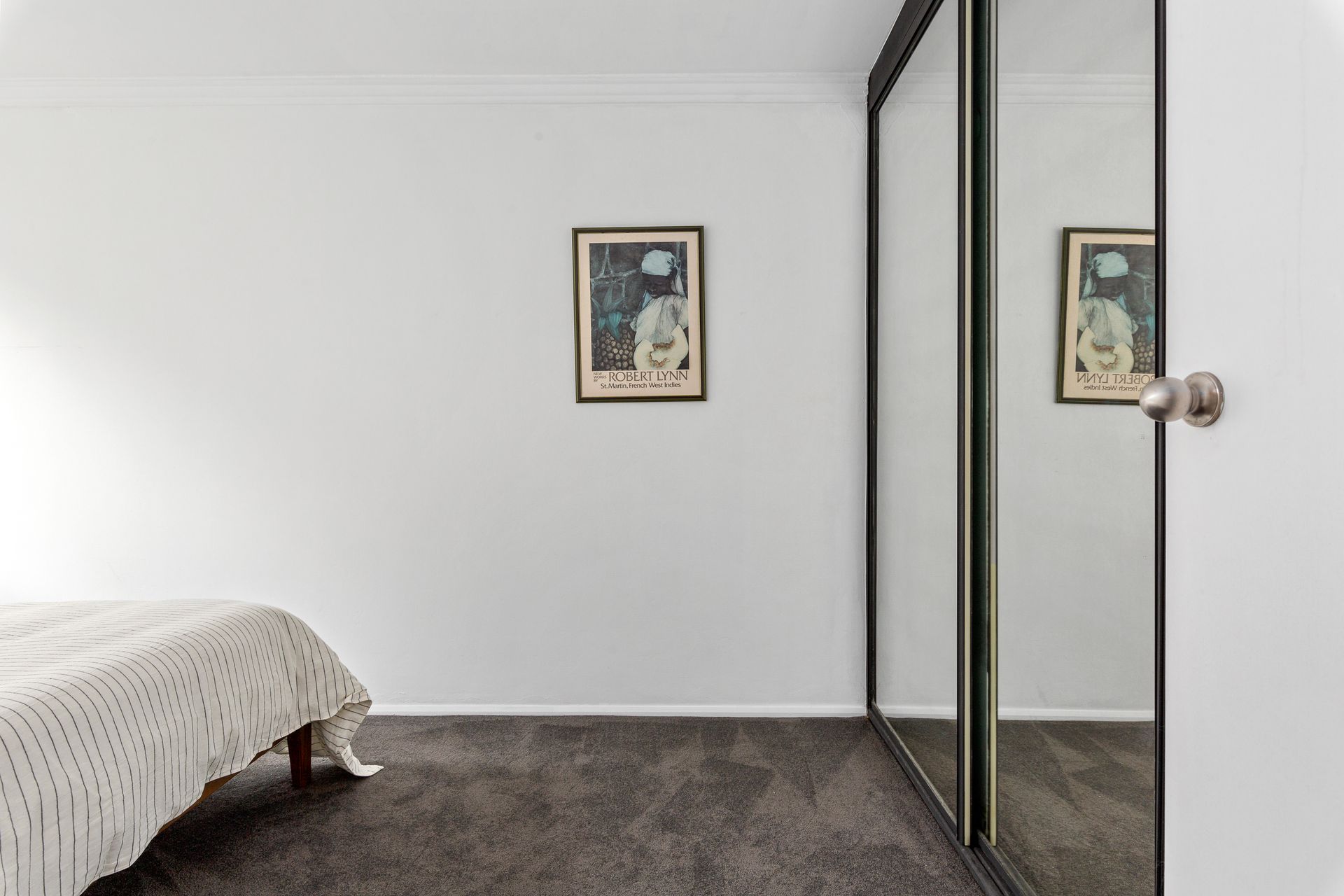 Minimal bedroom with a bed, framed wall art, and mirrored closet doors.
