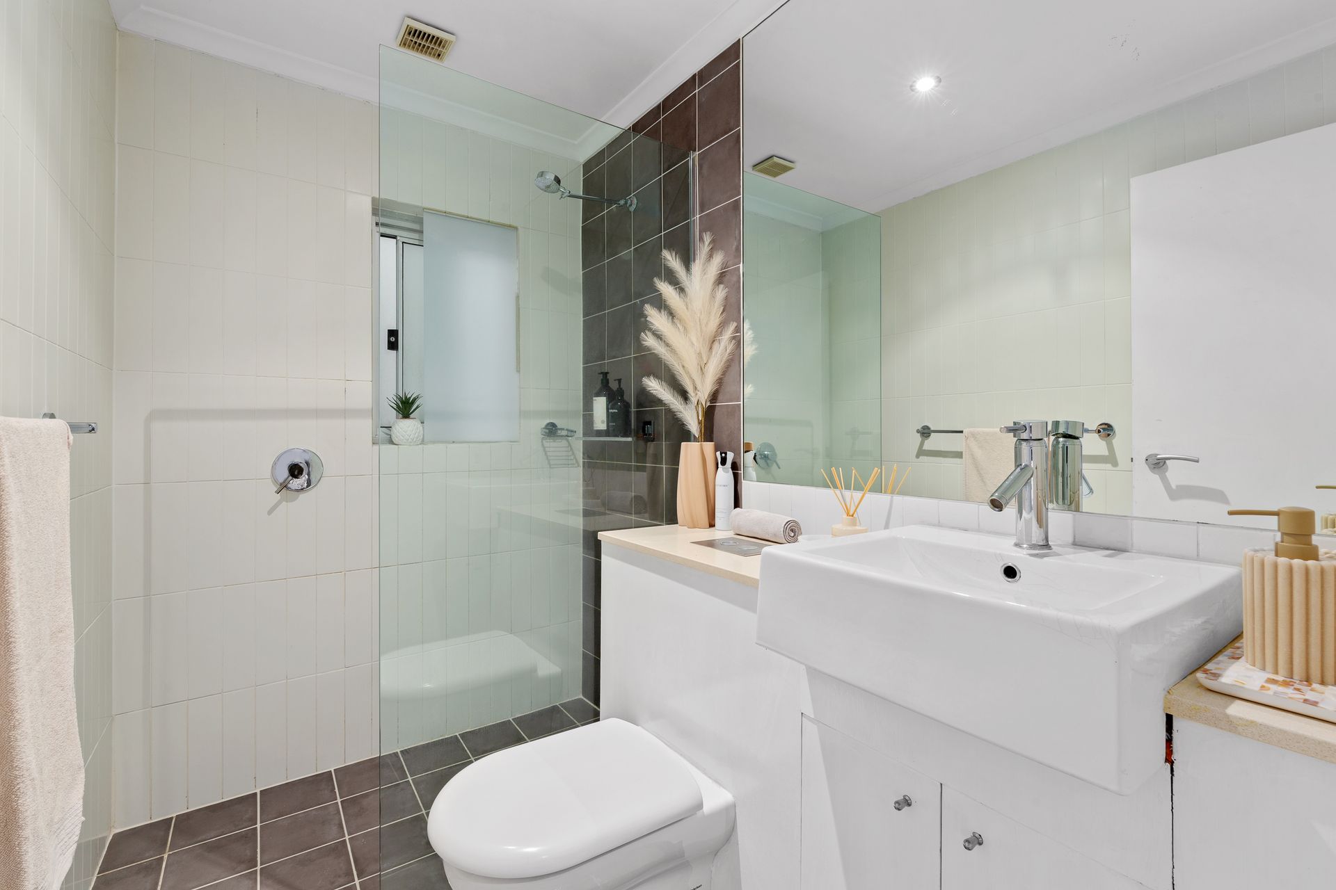 Modern white bathroom with glass shower, wall-mounted sink, and toilet