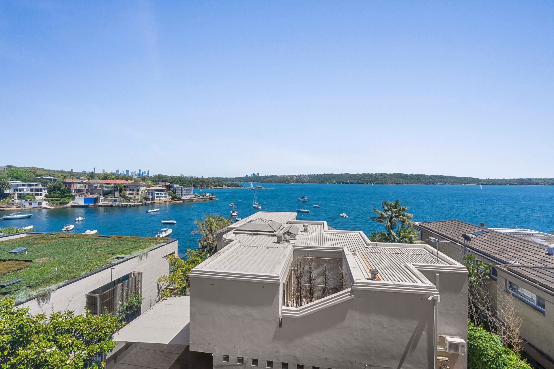 Harbor view with blue water, boats, and white coastal buildings under a clear sky