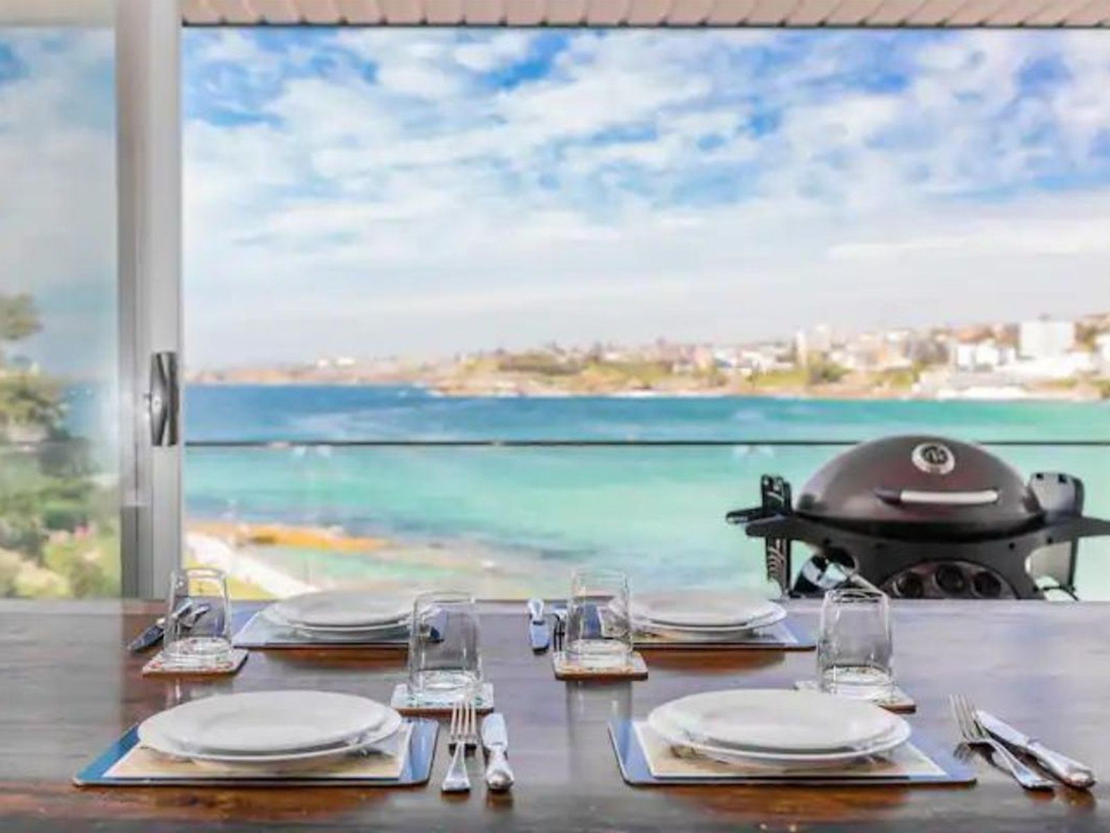 Dining table with plates overlooking a turquoise ocean and beach through a large window