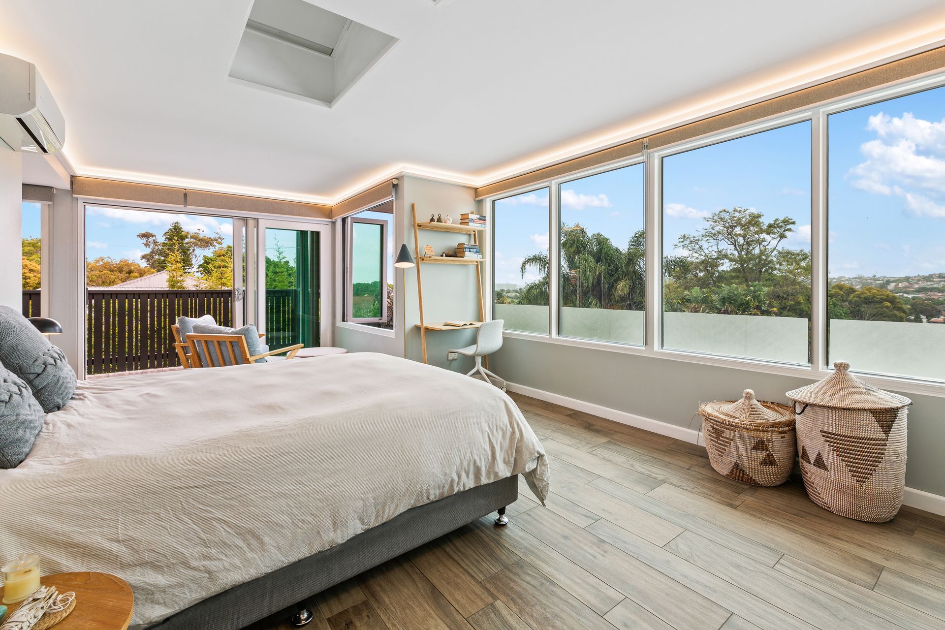 Bright bedroom with large windows, a bed, woven stools, and oceanfront or lakeside views