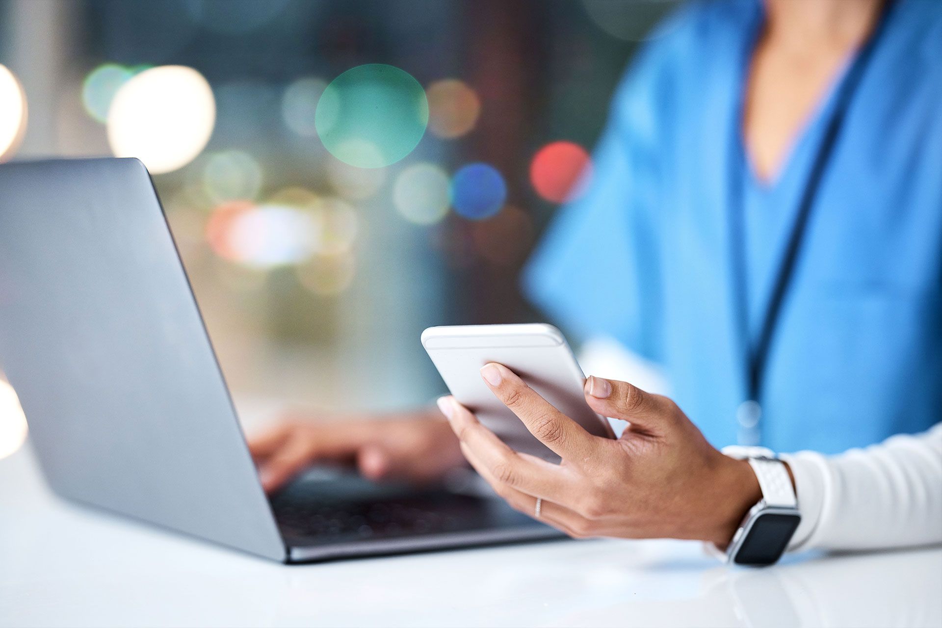 Eine Krankenschwester telefoniert und benutzt gleichzeitig einen Laptop.