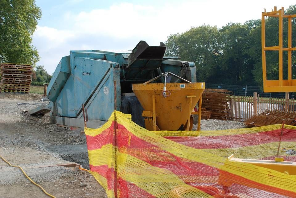 Chantier de construction avec une bétonnière et des clôtures de sécurité.