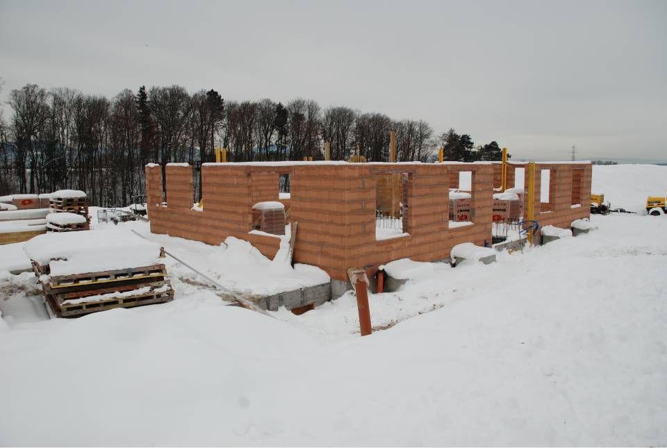 Chantier de construction d'un bâtiment en briques en hiver ; le sol est recouvert de neige.