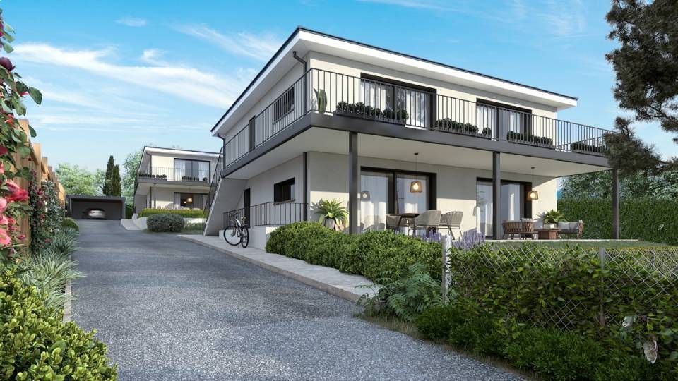Maisons modernes à deux étages avec des finitions noires, des balcons et une allée bordée de verdure sous un ciel bleu.