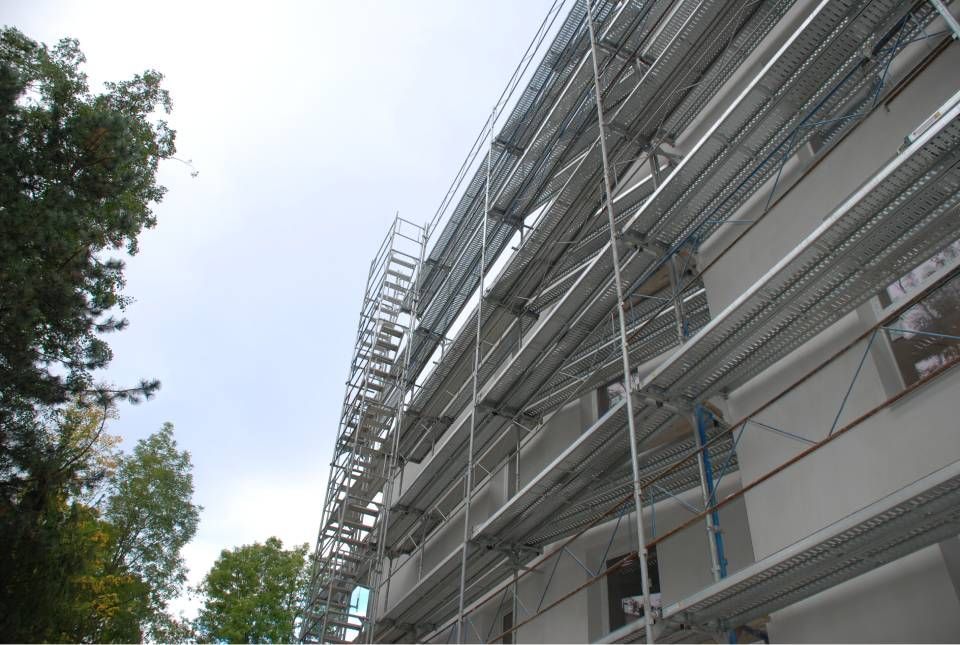 Échafaudages sur le côté d'un bâtiment sous un ciel nuageux.