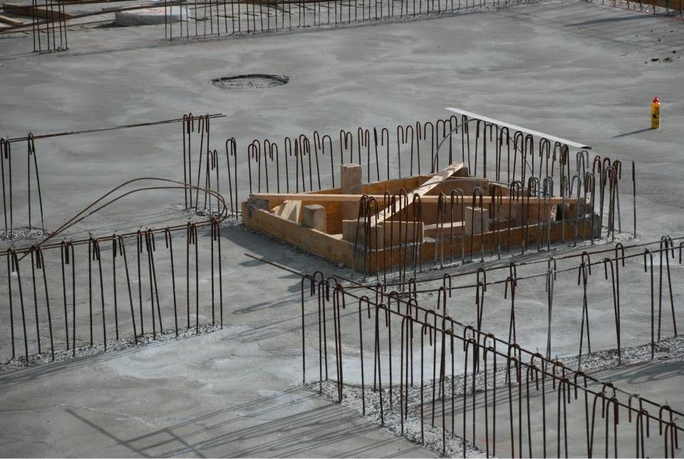 Chantier de construction : Armature d'armatures entourant un coffrage en bois sur une fondation en béton.