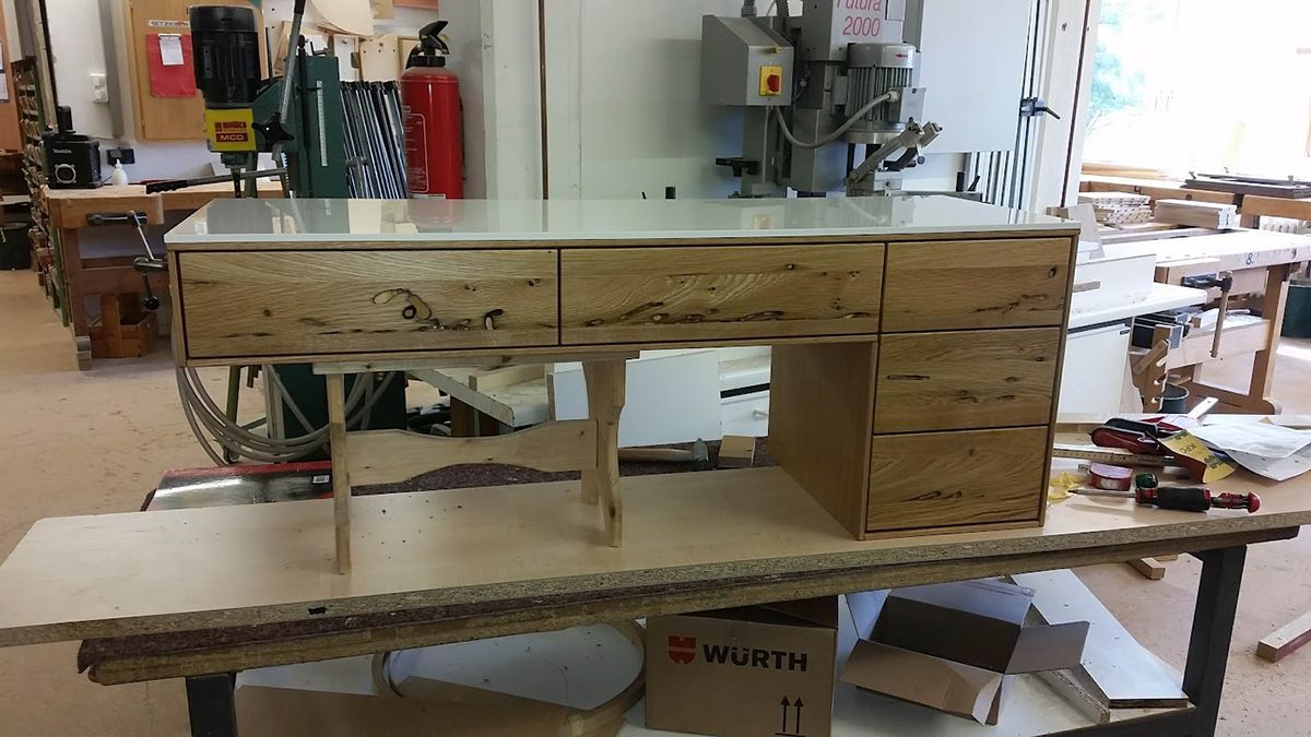Schreibtisch aus hellem Holz mit Schubladen im Werkstatt-Setting.