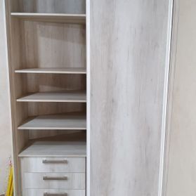 Un armario blanco con puertas correderas y estantes y cajones.