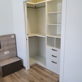 Un vestidor con estantes y cajones en un dormitorio.