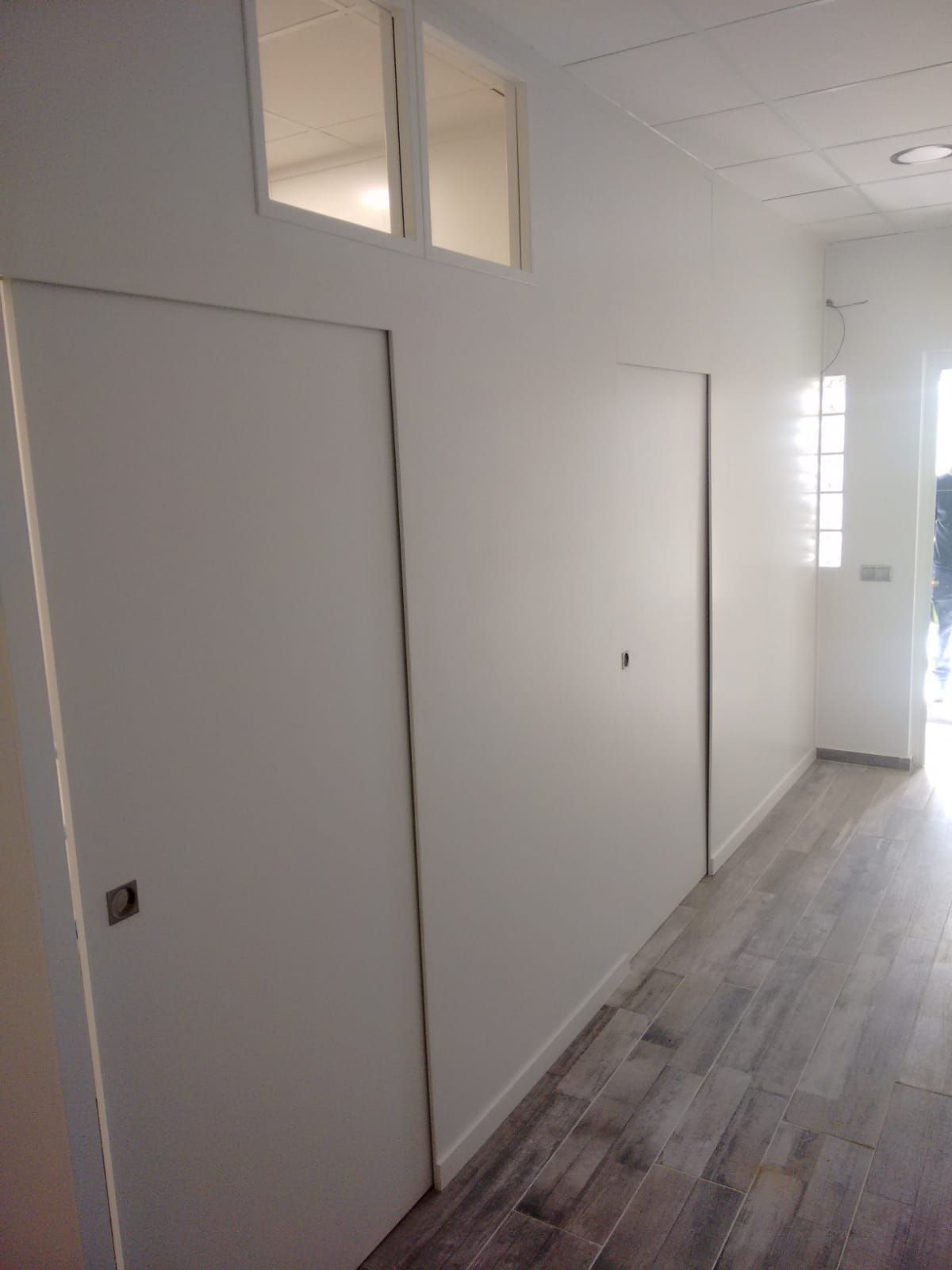 Un largo pasillo con paredes blancas y suelos de madera.