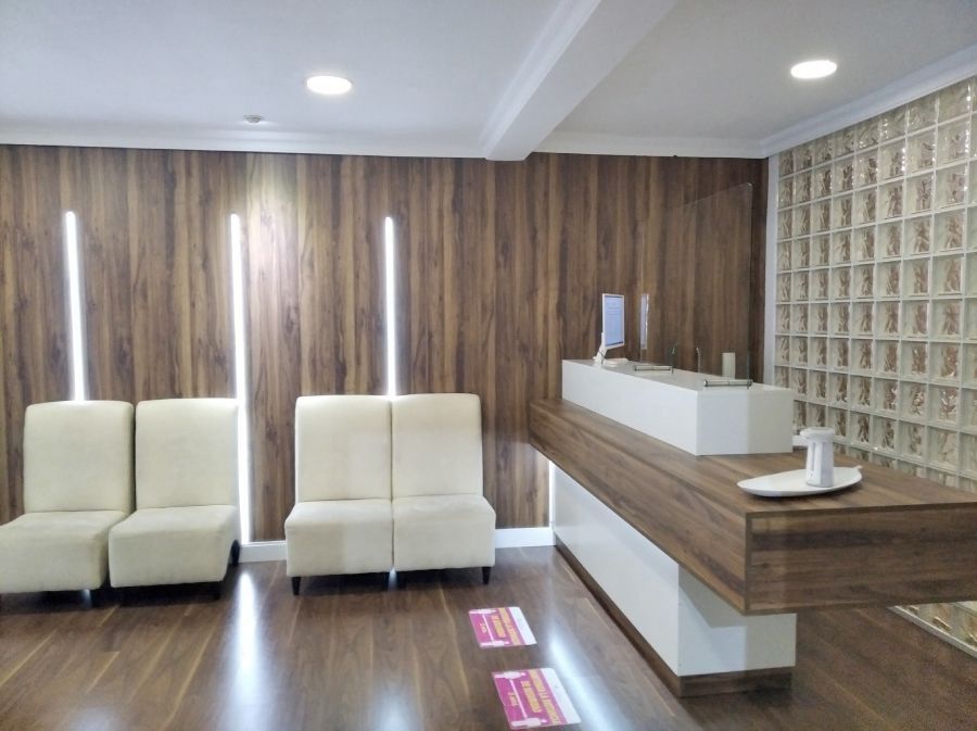 Una sala de espera con sillas blancas y un mostrador de madera.