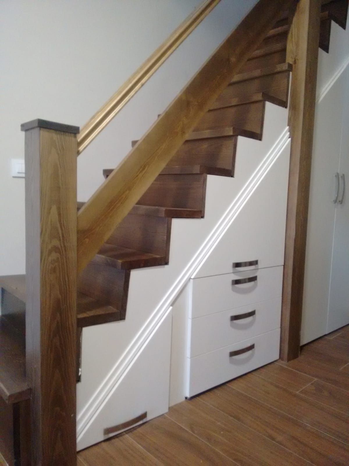 Una escalera de madera con cajones blancos debajo.