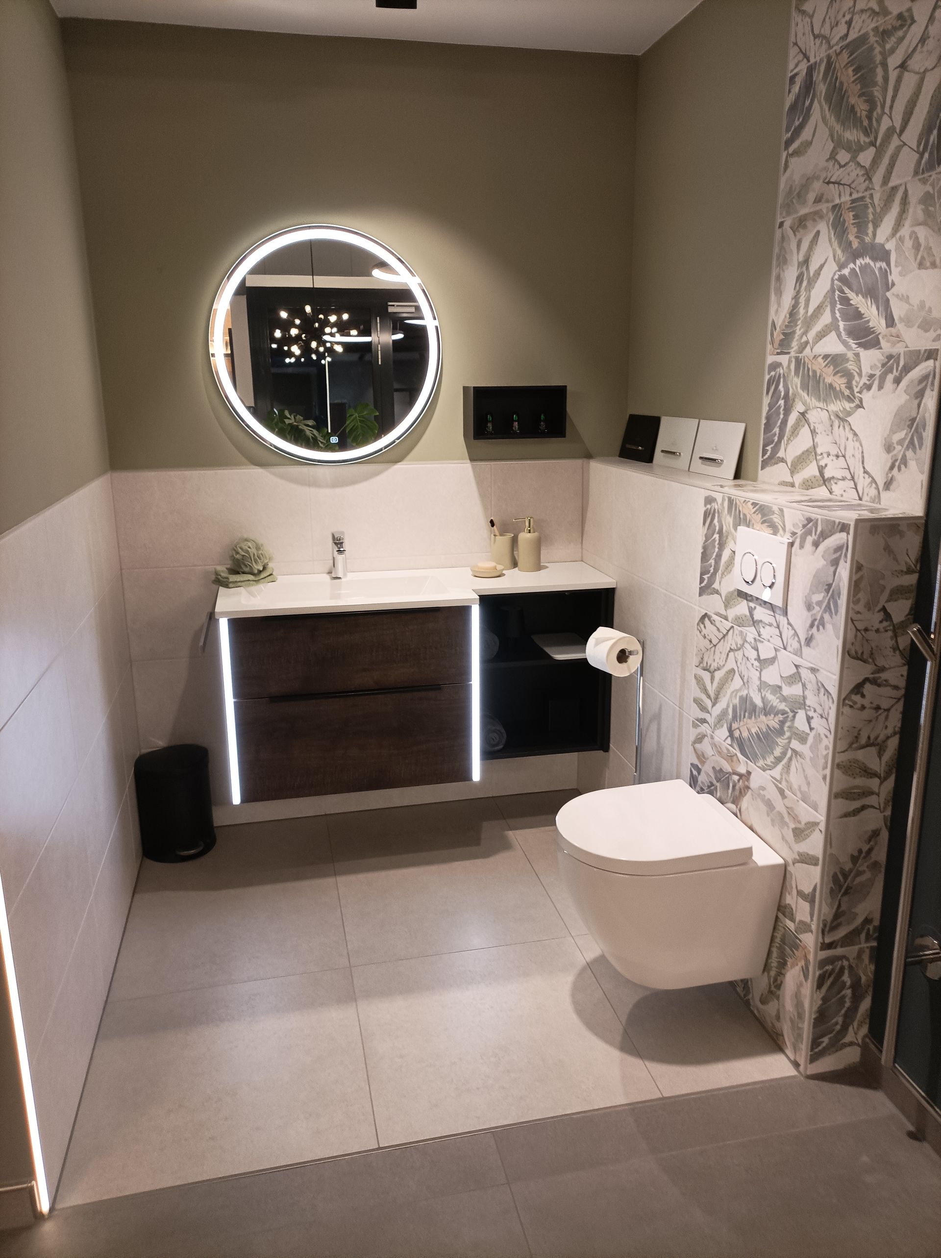 Modernes Bad mit beleuchtetem Rundspiegel und edler Wandgestaltung.