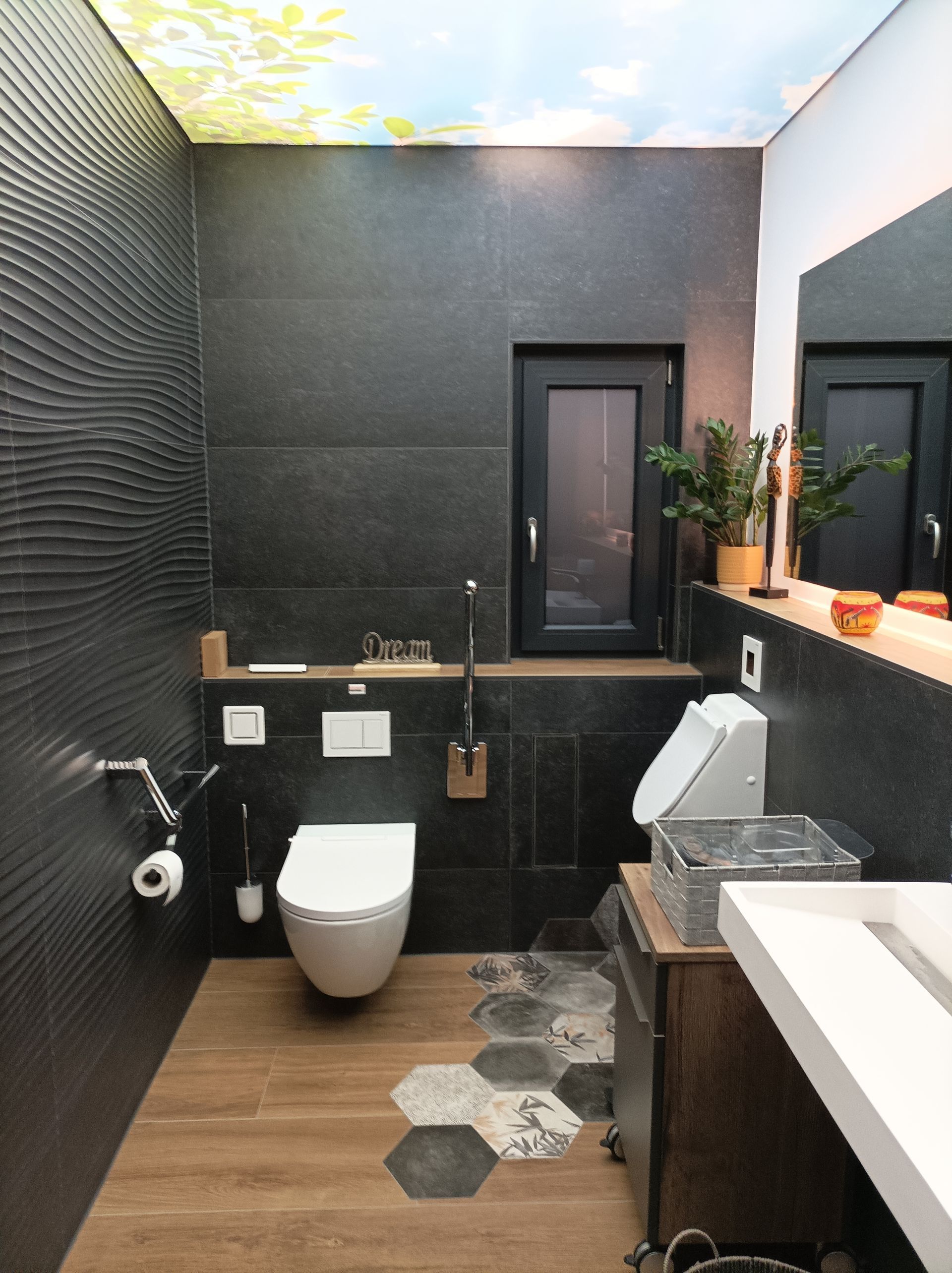 Badezimmer mit großformatigen Fliesen und beleuchtetem Deckenmotiv.