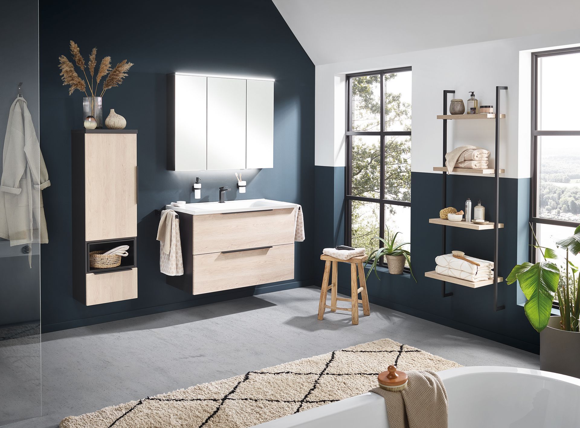 Elegantes Bad in dunklen Tönen mit Waschtisch, Spiegel und freistehender Dekoration.