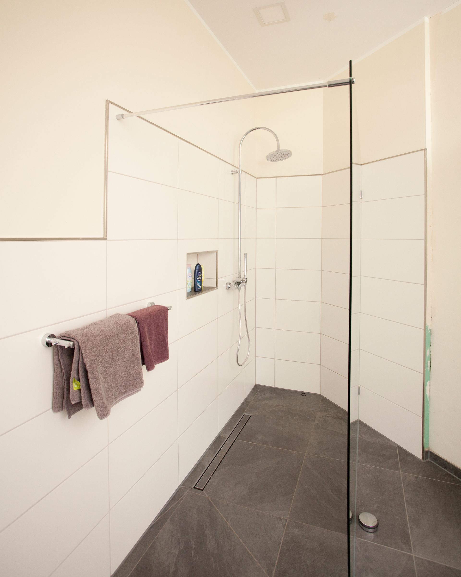 Modernes Badezimmer mit großer, ebenerdiger Dusche und Holzoptik-Boden.