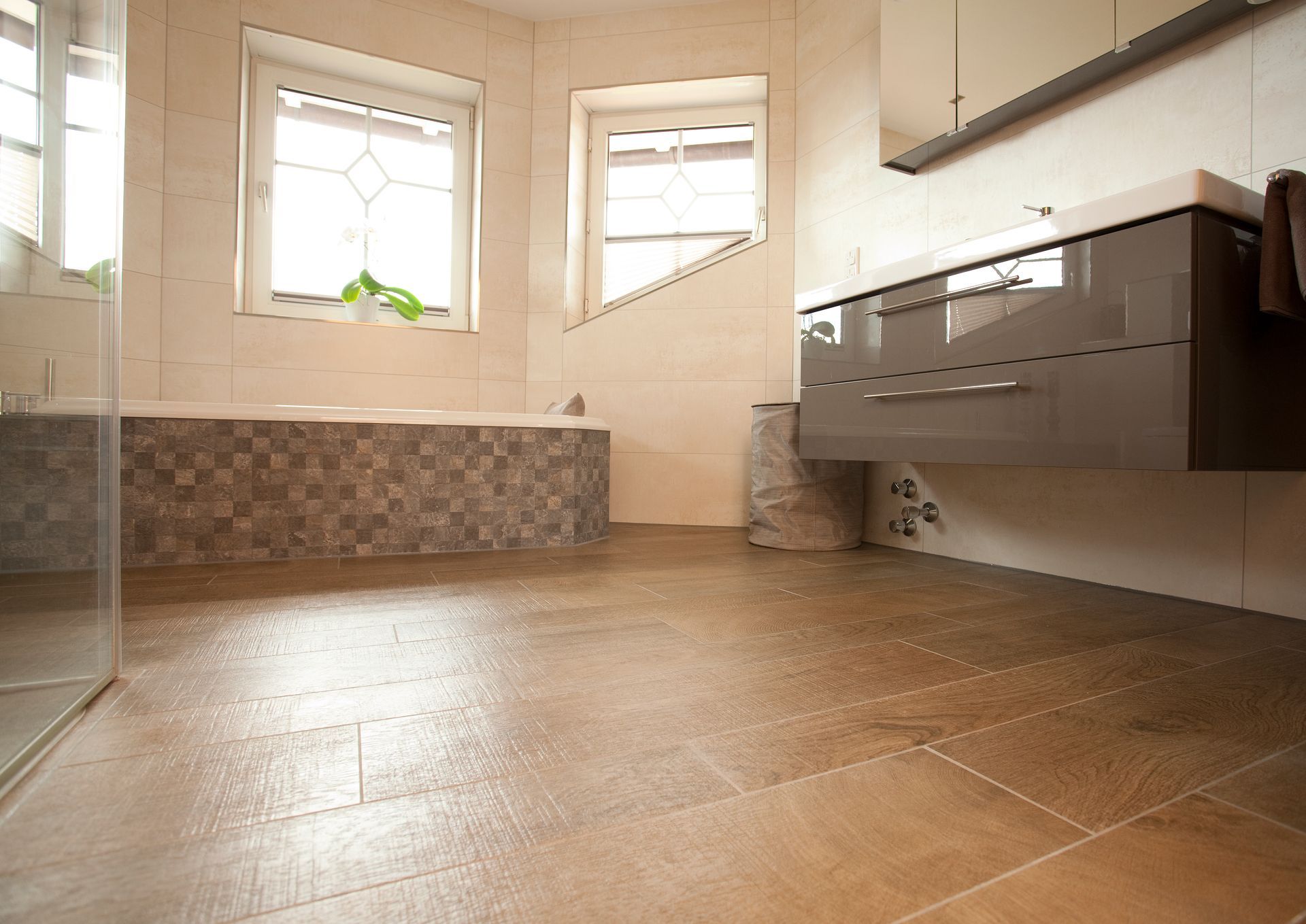 Großzügiges Badezimmer mit beigen Bodenfliesen, Badewanne und modernen Waschtischen.