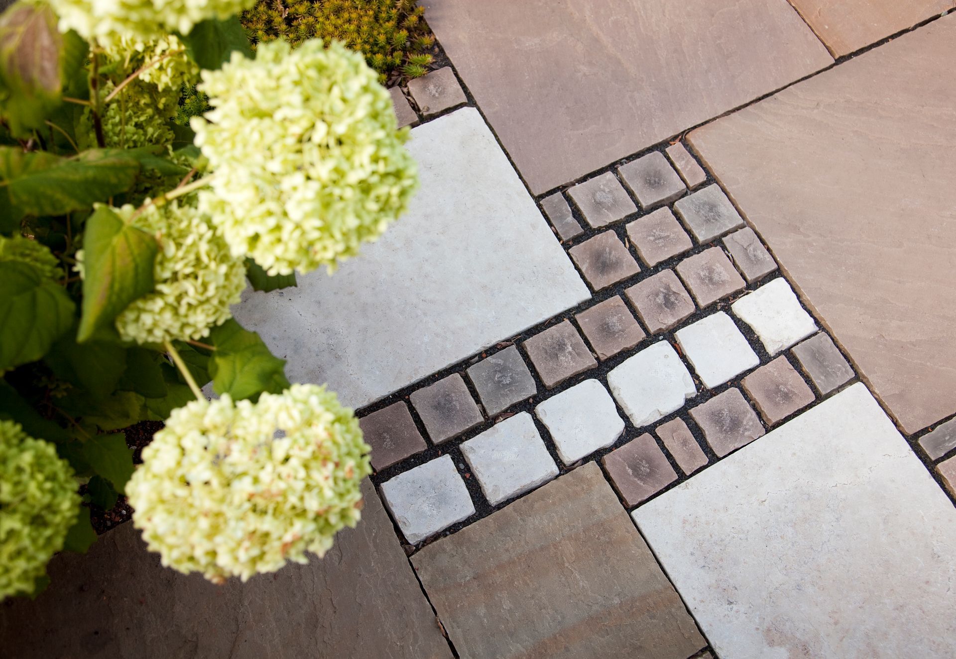 Kombination aus unterschiedlichen Pflastersteinen und Mosaikmustern auf einer Terrasse.