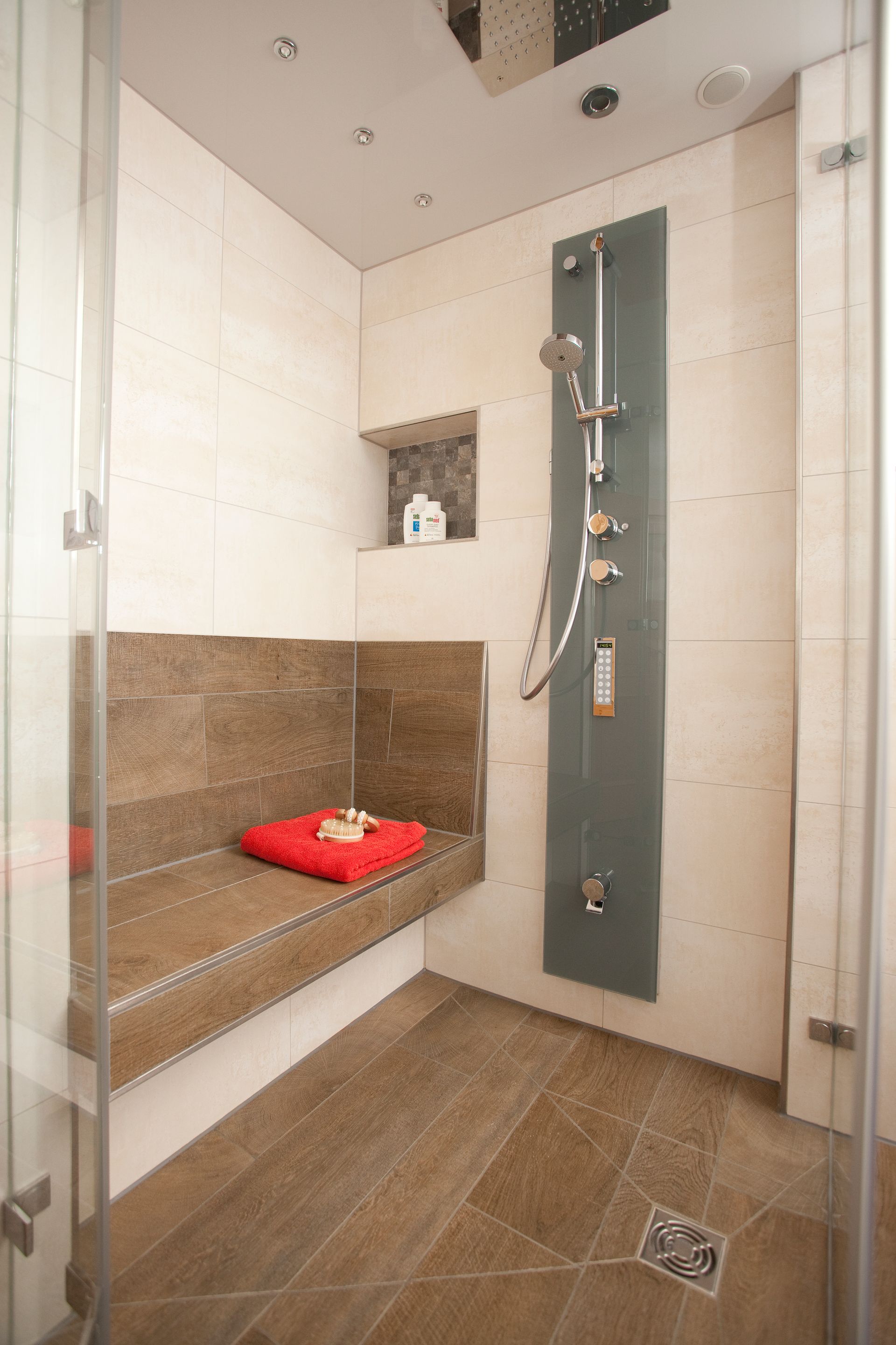 Eckdusche mit Sitzbank, moderner Armatur und heller Wandverkleidung.