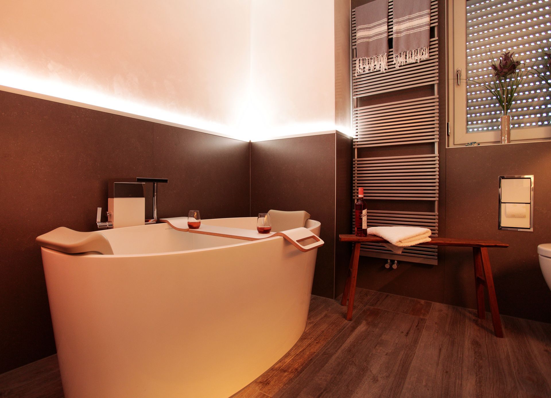 Stimmungsvolles Bad mit warmem Licht, Waschtisch und Holzoptik.