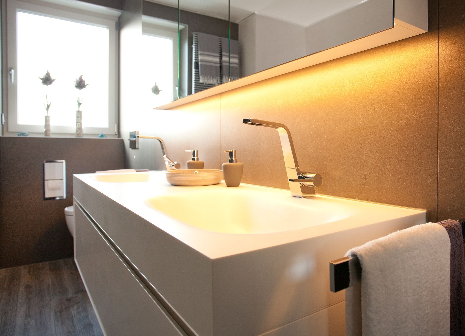 Waschtisch mit beleuchtetem Spiegel und modernen Badaccessoires.