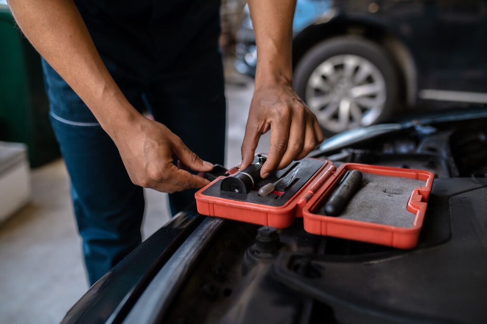 Un hombre está trabajando en el motor de un coche en un garaje.