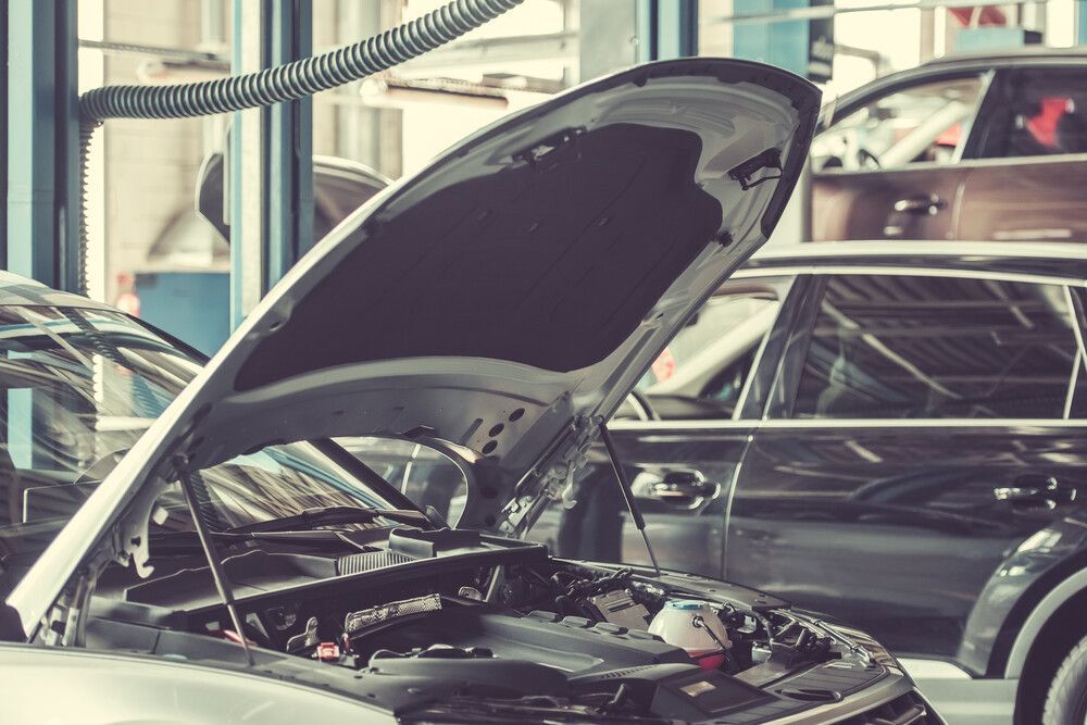El capó de un coche está abierto en un garaje.