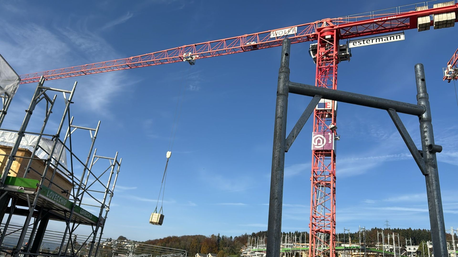Eine Baustelle mit Kränen und Gerüsten und einem blauen Himmel im Hintergrund.