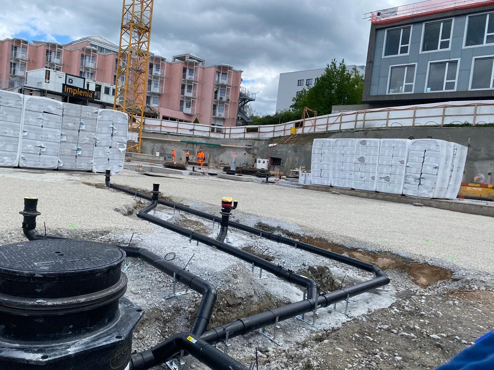 Eine Baustelle mit einem Gebäude im Hintergrund und einem Kran im Hintergrund.