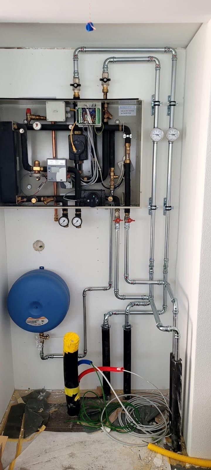 Ein Raum mit vielen Rohren und einem blauen Tank.